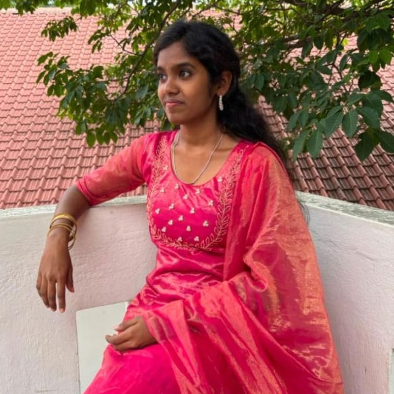 Harshitha in a pink salwar kameez, looking off to the side